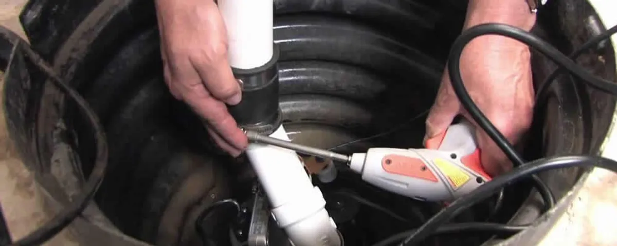 Sump pump installation technician connecting PVC discharge piping in San Mateo, CA